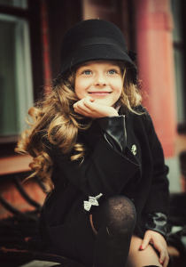 Happy baby girl in a black hat and coat smiling